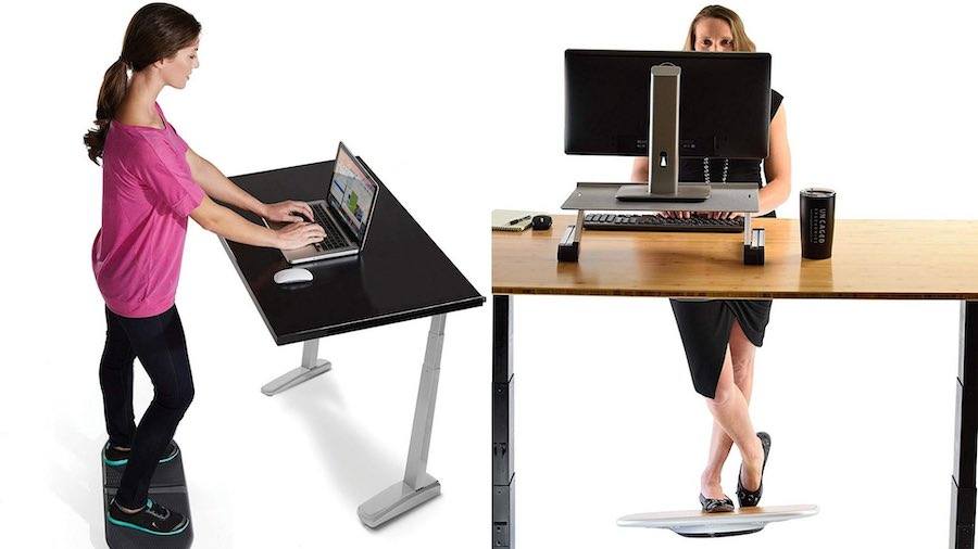 two women using balance boards at stand up desk in office